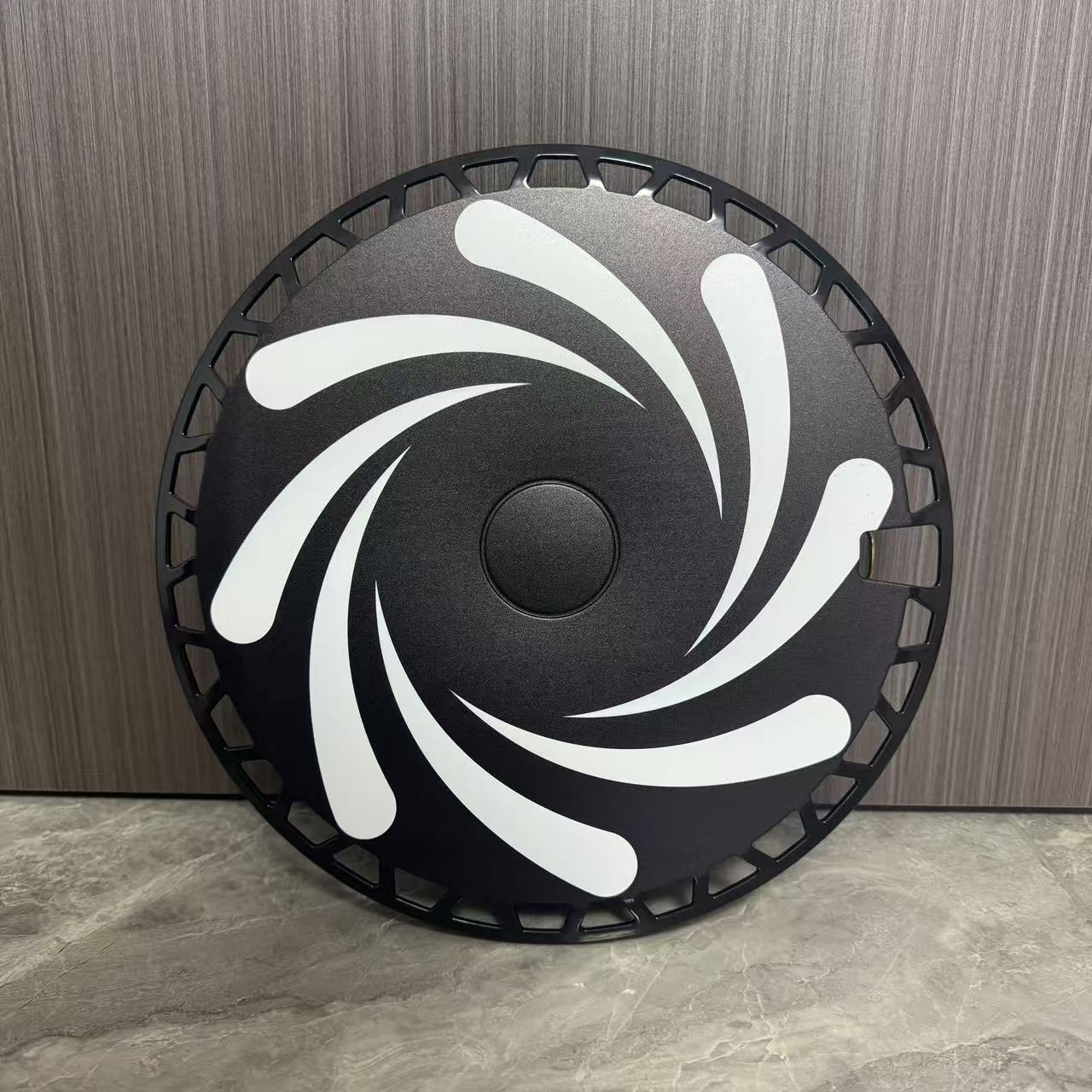 Gros plan d'un enjoliveur Rim Crew imprimé, motif tourbillon blanc sur fond noir